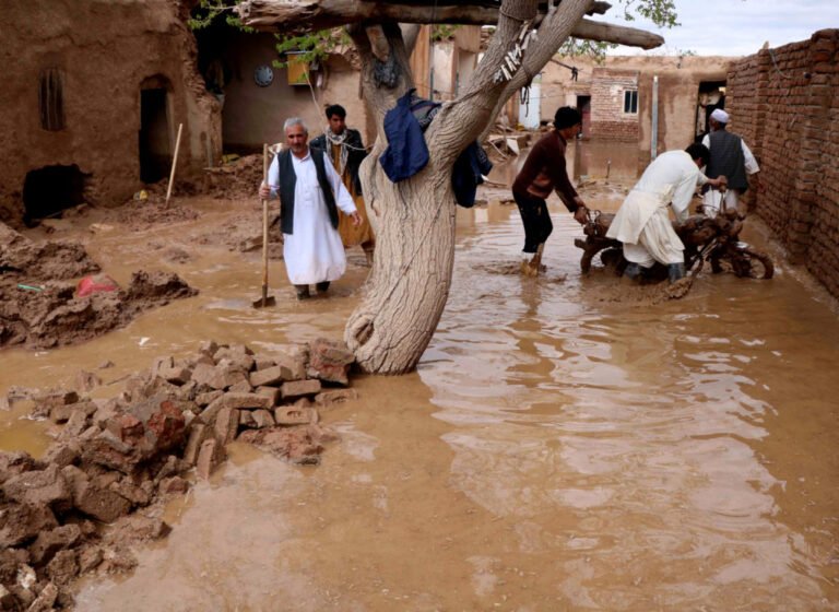People salvage items from a house destroyed by flood in Enjil district of Herat province